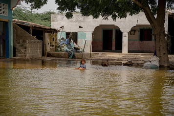 طفل يجلس وسط مياه الفيضانات المحيطة بمبنى في باكستان.