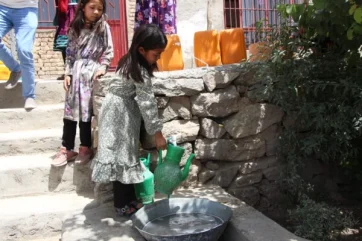 ابنة خديجة تجمع المياه خارج منزل العائلة في أفغانستان